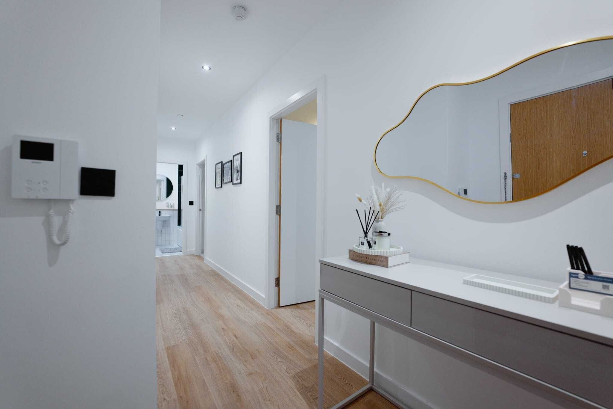 A modern bathroom with a white vanity, a large mirror, and a telephone.