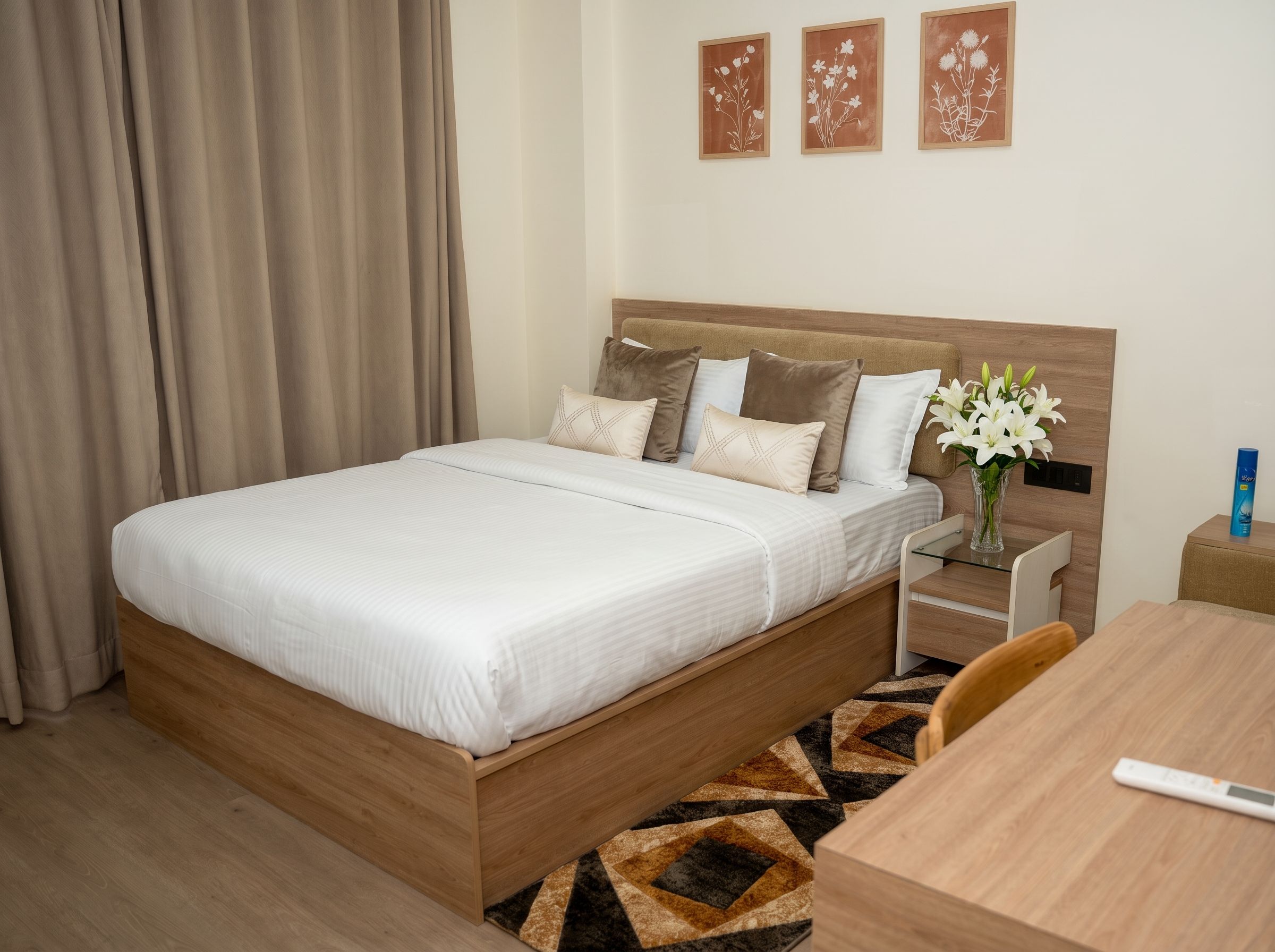 Quarto de hotel com cama, mesa de cabeceira e um vaso de flores.