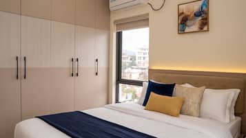 Una habitación de hotel con cama, ventana y aire acondicionado.