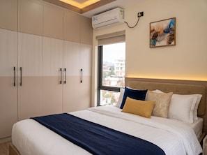 Una habitación de hotel con cama, ventana y aire acondicionado.