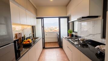 A modern kitchen with a view of a cityscape through a sliding door.