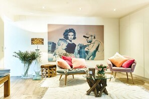 Ein modernes Wohnzimmer mit einer Couch, Sesseln, einem Couchtisch und einem großen Gemälde an der Wand.