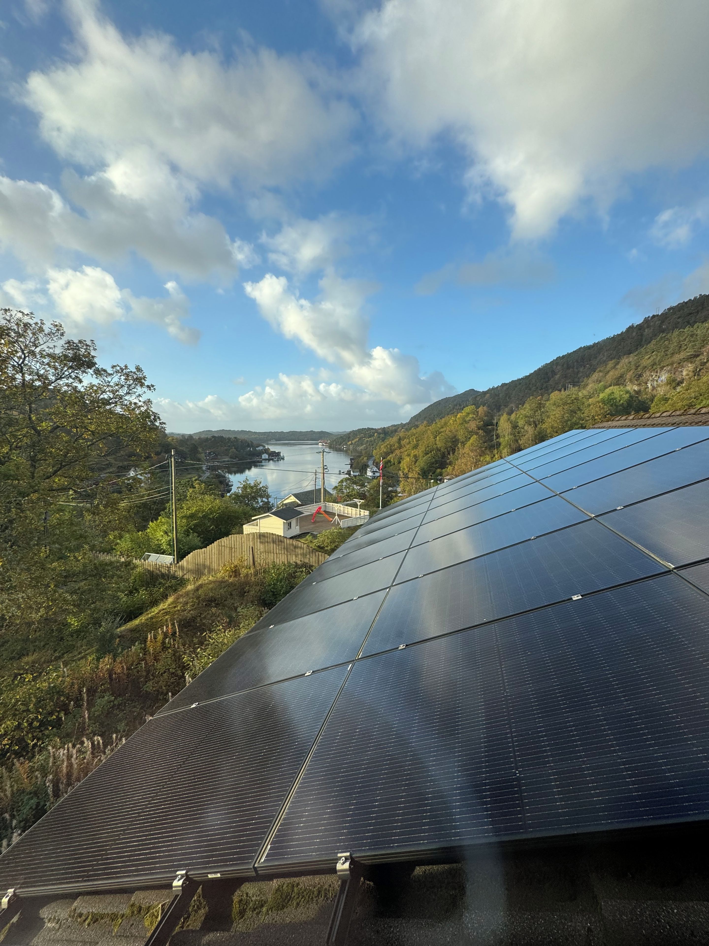 Solar panels on a roof, a lake, and a forested hillside.