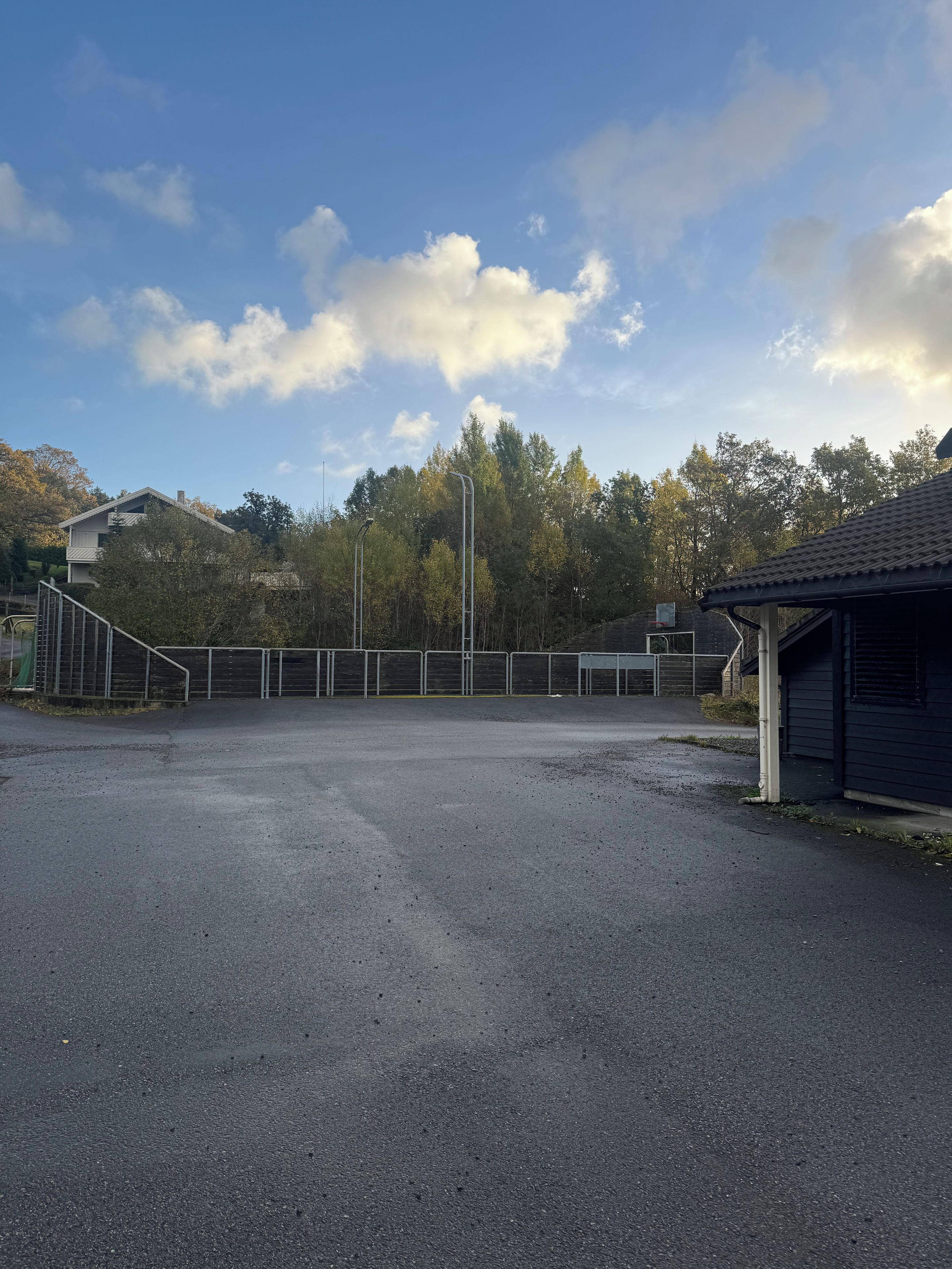 A parking lot with a building on the right and trees in the background.