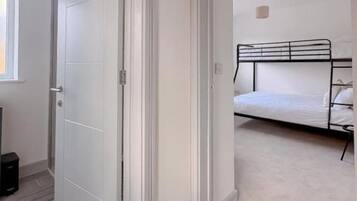 A bedroom with a bed, a door, and a small window.
