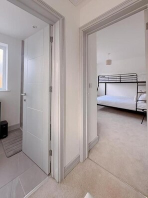 A bedroom with a bed, a door, and a small window.