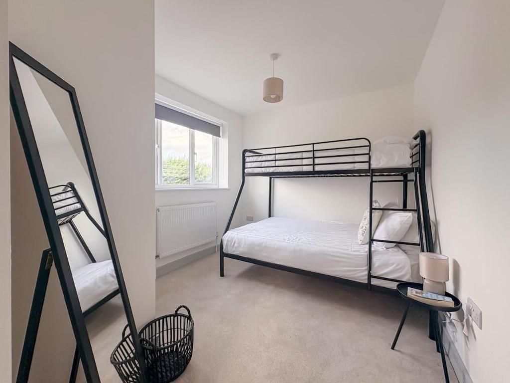 A bunk bed room with a window, a standing desk, and a lamp.