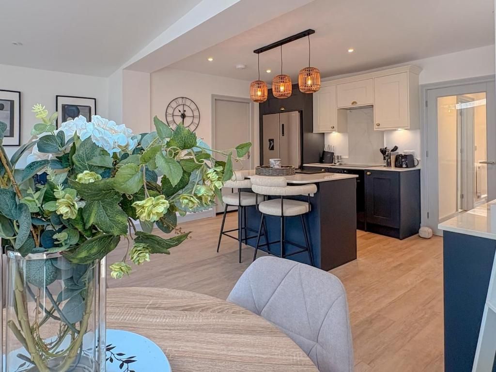 A modern kitchen with a central island, pendant lighting, and a dining area with a table and chairs.