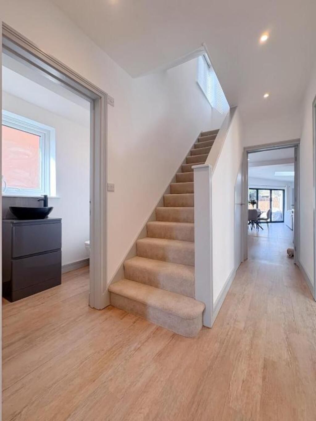A modern interior with a carpeted staircase, wooden flooring, and a minimalist design.