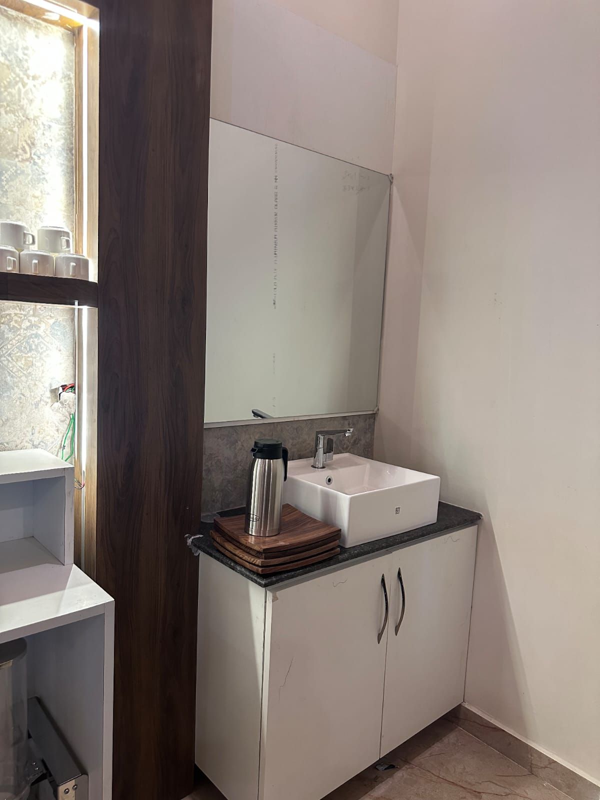 Un baño con un lavabo blanco, un espejo encima y un mueble de madera debajo.