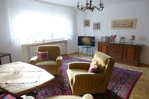Una sala de estar con televisor, un mueble y una alfombra estampada.