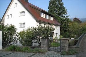 A two-story house with a sloped roof, a stone gate, and a paved driveway. - Holiday apartment with 2 bedrooms (Freiburg)