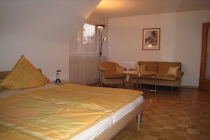 A hotel room with a bed, a sofa, a small table, and a floor lamp. - Holiday apartment with 2 bedrooms (Freiburg)