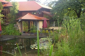 A traditional building with a pond in front, surrounded by lush greenery. - Holiday apartment with 1 bedroom (Geislingen)