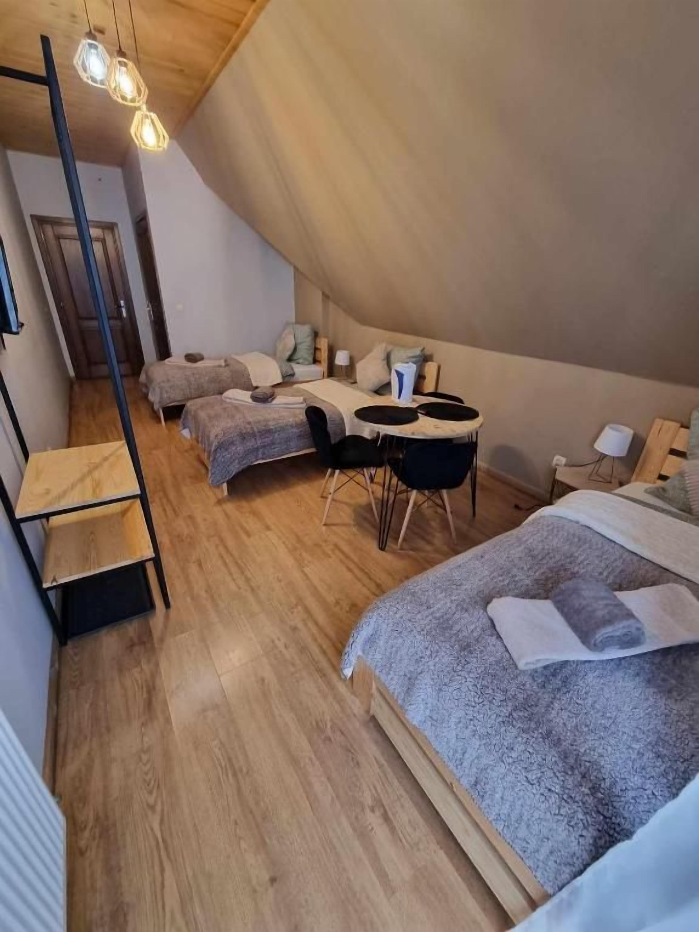 Ein gemütliches Schlafzimmer mit schrägen Wänden, einem Bett, einem Schreibtisch und einem Stuhl.