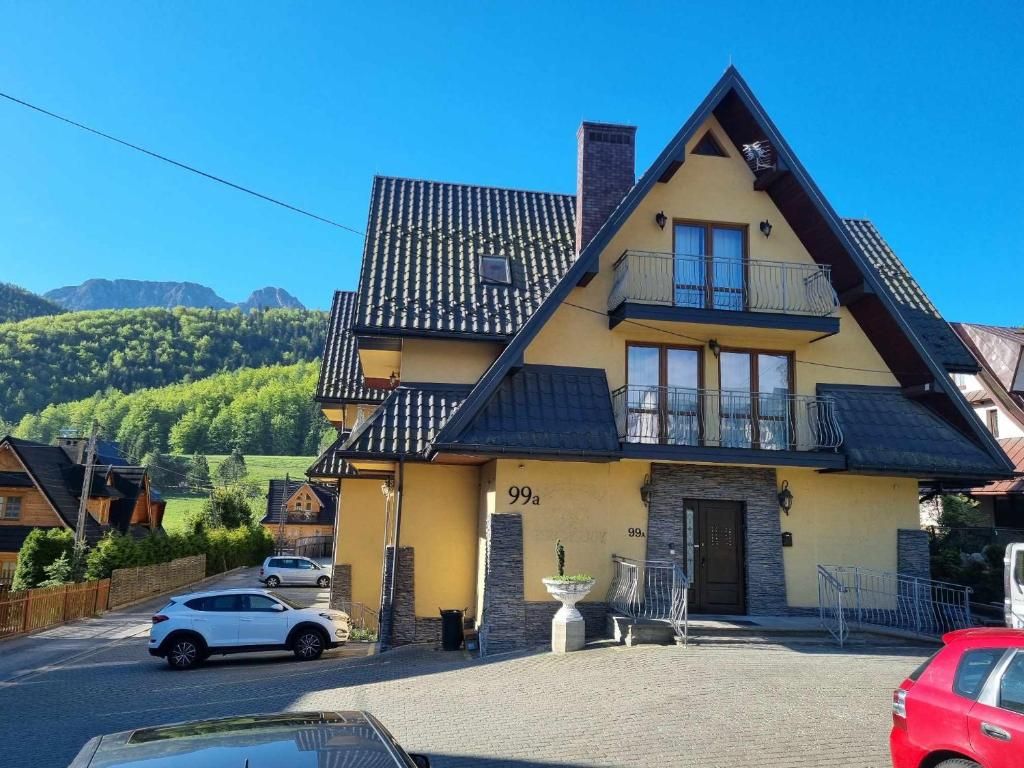 Ein zweistöckiges Haus mit Balkon, Schornstein und der Hausnummer 99a an der Fassade.