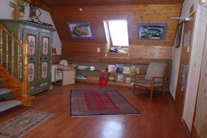 Ein Zimmer mit einer Holztreppe, einem Schreibtisch mit Büchern, einem Stuhl und einem Fenster mit Blick.