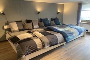Ein modernes Schlafzimmer mit einem großen Bett, Nachttischlampen und einem Fenster mit Vorhängen.