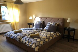 Een slaapkamer met een groot bed, twee nachtkastjes, een raam met gordijnen en een radiator.