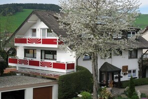 A two-story building with a balcony, a garden with a tree, and a small gazebo. - "Spatz" at the Dold guesthouse (St. Peter)
