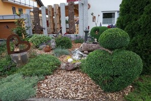 A garden with various plants, a wooden fence, and a small pond. - "Spatz" at the Dold guesthouse (St. Peter)