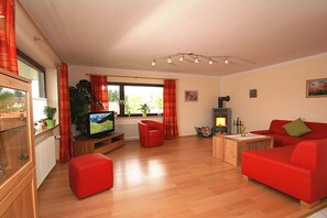 A living room with a television, red sofa, and a fireplace. - "Spatz" at the Dold guesthouse (St. Peter)