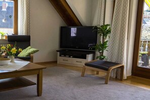 A living room with a television, a sofa, a coffee table, and a bench. - OG House Thum am Kaiserstuhl (Bötzingen)