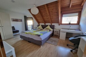 Ein Schlafzimmer mit einem Bett, einem Schreibtisch, einem Stuhl, einer Heizung und einem Fenster mit Jalousien.