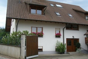 Ein zweistöckiges Haus mit einem Ziegeldach, Holztüren und Fenstern mit Fensterläden.