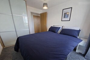 Ein Schlafzimmer mit einem Bett, einem Kleiderschrank, einer Tür und einem gerahmten Bild an der Wand.