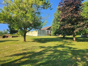A house with a sloped roof, surrounded by a well-maintained lawn and trees. - Holiday Home 'Gîte Lauberoye' with Private Terrace, Private Garden and Wi-Fi (Saint-Pierremont)