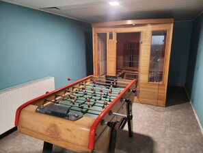 A foosball table in a room with blue walls and a wooden door. - Holiday Home 'Gîte Lauberoye' with Private Terrace, Private Garden and Wi-Fi (Saint-Pierremont)