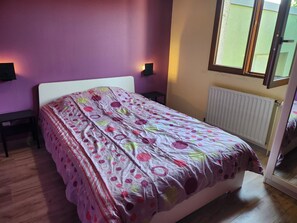 A bedroom with a bed, two bedside tables, a window with a view, and a radiator. - Holiday Home 'Gîte Lauberoye' with Private Terrace, Private Garden and Wi-Fi (Saint-Pierremont)