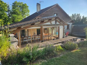 A house with a covered patio, a dining area, and a trampoline. - Holiday Home 'Gîte Lauberoye' with Private Terrace, Private Garden and Wi-Fi (Saint-Pierremont)