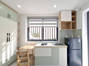 A modern kitchen with a window, a sink, a refrigerator, and wooden furniture. - Olive House by the Beach - Elevator & Kitchen (Vung tau)