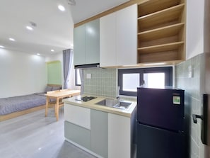 A compact kitchen with a refrigerator, sink, and a window above the counter. - Olive House by the Beach - Elevator & Kitchen (Vung tau)