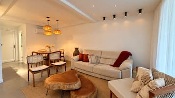 Uma sala de estar moderna com sofá, mesa de centro e área de jantar.