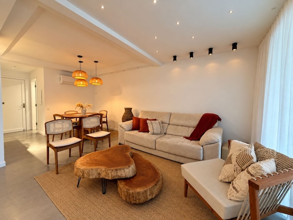 A modern living room with a sofa, coffee table, and dining area.