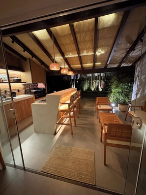 A modern kitchen with a bar area, wooden furniture, and a view of the outdoors. - Porto Frade Stay • Angra • Privet Gourmet Lounge • Golf, Marina & Beach Access (Angra dos Reis)