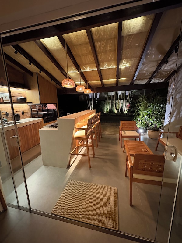 A modern kitchen with a bar area, wooden furniture, and a view of the outdoors.