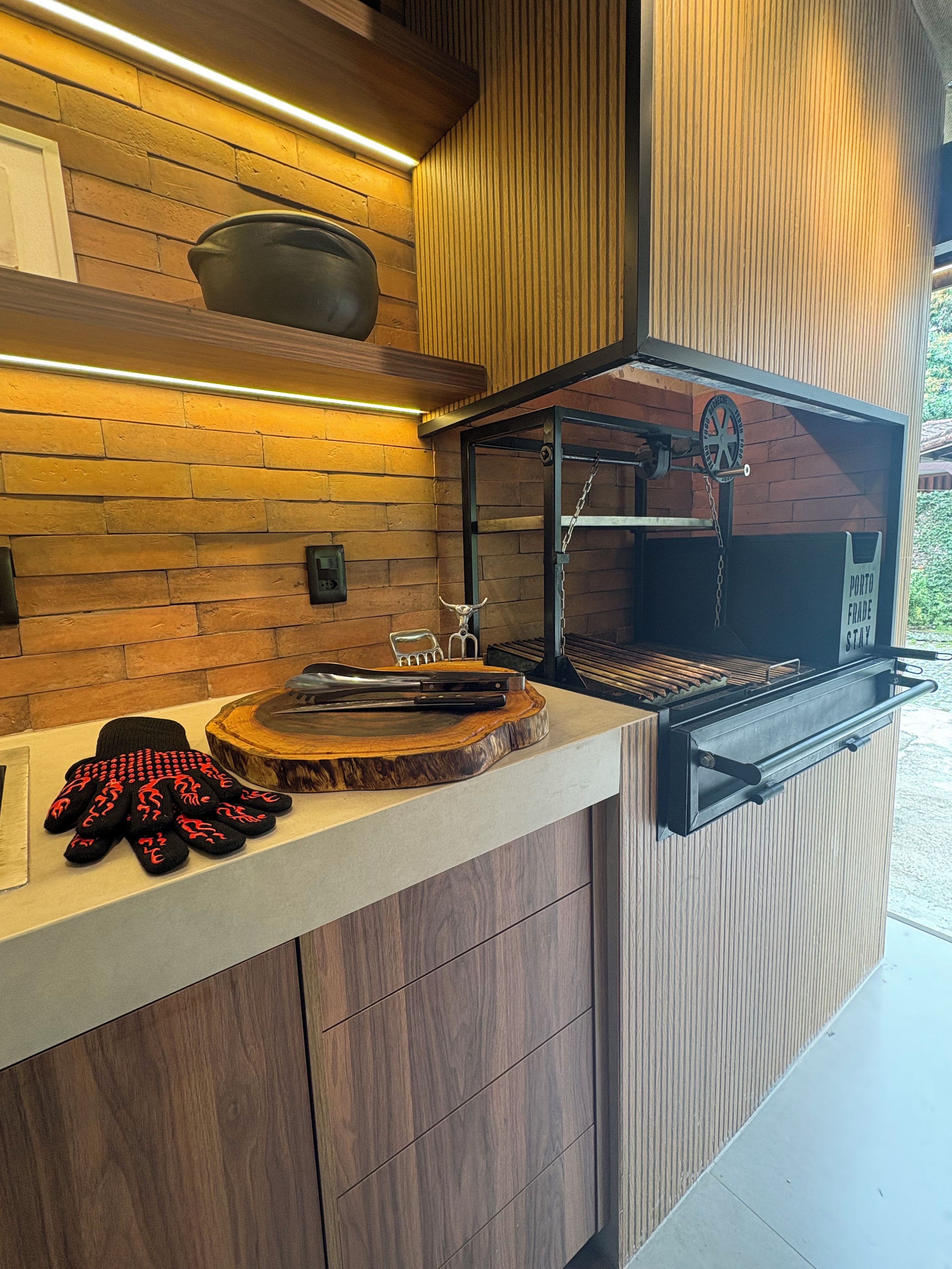 A modern kitchen with a brick wall backsplash, wooden cabinets, and a built-in grill station.