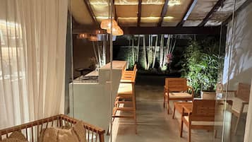 Interior moderno com divisória de vidro, mobiliário de madeira e vista para um jardim.
