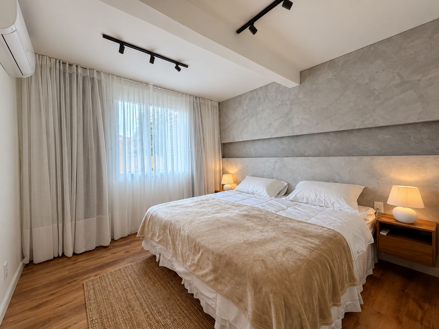 Une chambre moderne avec un grand lit, des lampes de chevet, un luminaire au plafond et une fenêtre ornée de rideaux légers.