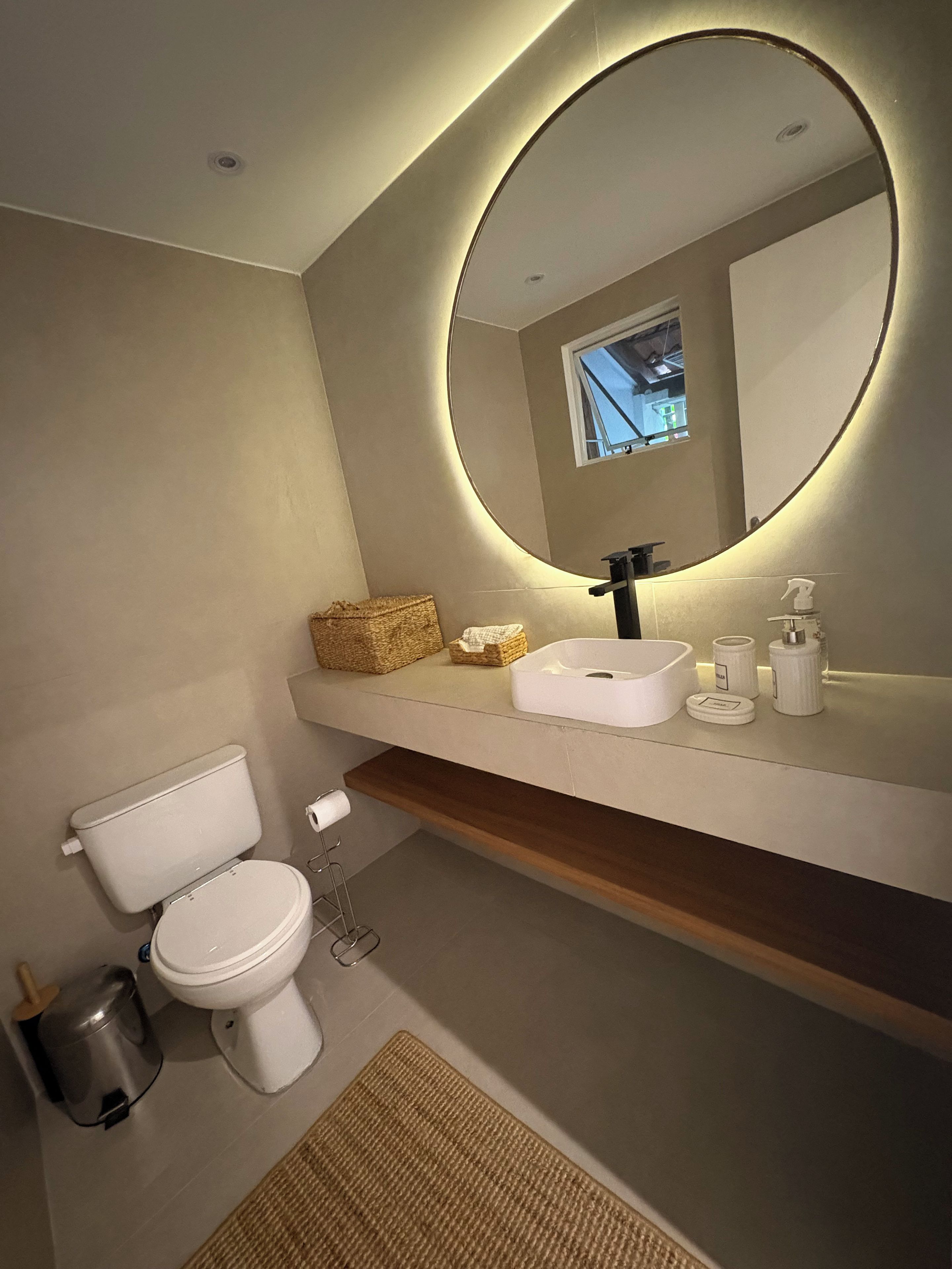 Een moderne badkamer met toilet, wastafel en spiegel.