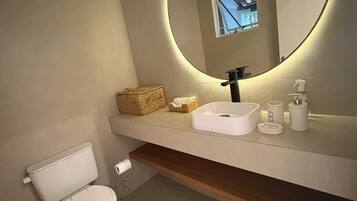Een moderne badkamer met toilet, wastafel en spiegel.