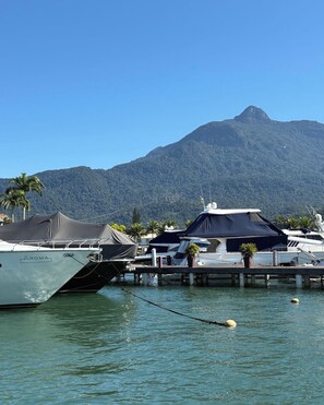 A marina with boats docked, a mountain in the background, and a clear sky. - Porto Frade Stay • Angra • Privet Gourmet Lounge • Golf, Marina & Beach Access (Angra dos Reis)