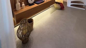 Uma sala de estar moderna com uma TV de tela plana fixada em uma parede de madeira, uma escada espiral branca e uma cesta trançada no chão.