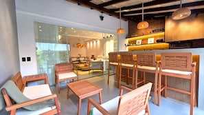 Un interior moderno con muebles de madera, una zona de bar y vistas a través de un ventanal.