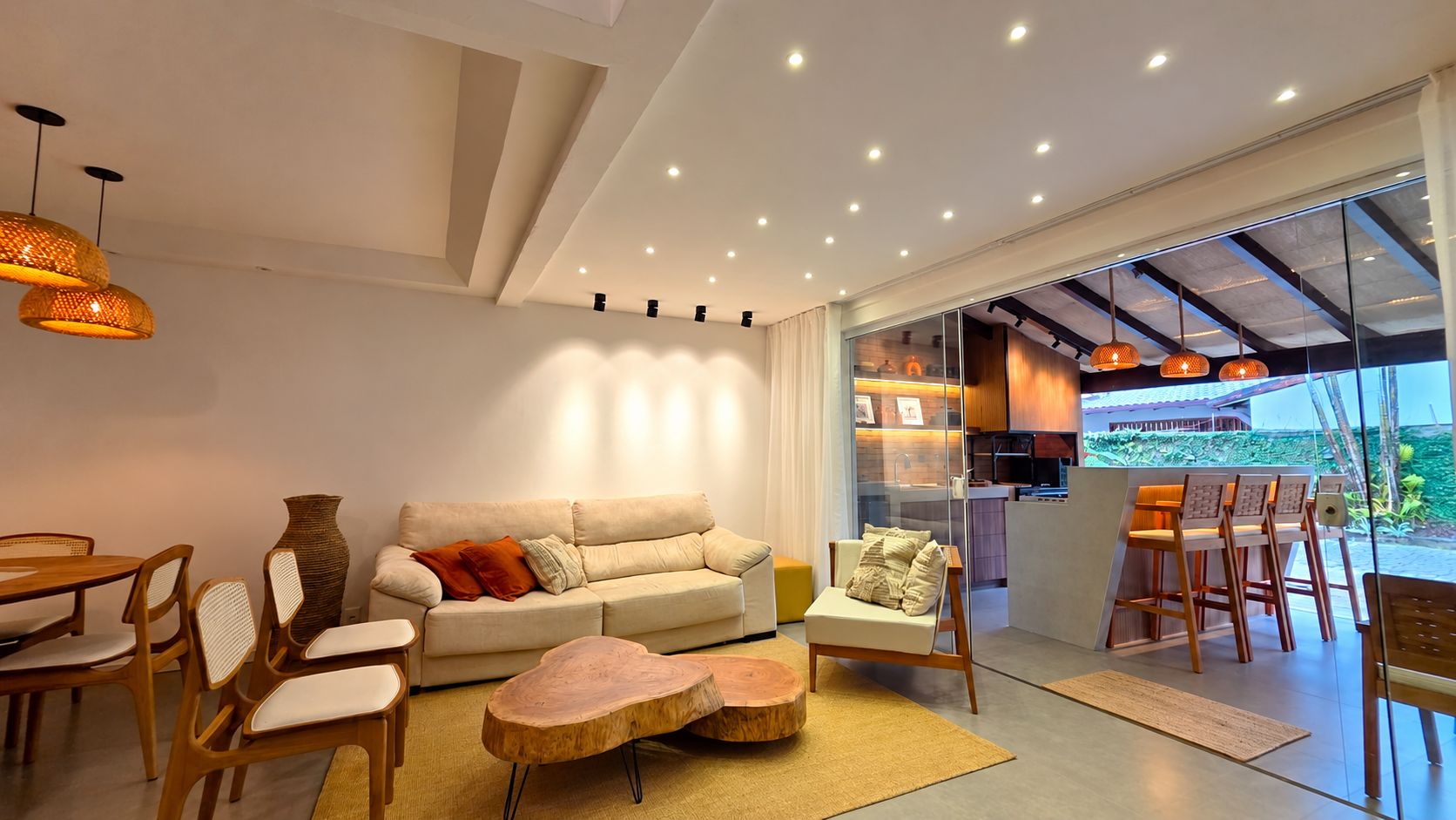 Uma sala de estar moderna com sofá, cadeiras, mesa de centro e área de jantar com mesa e cadeiras.