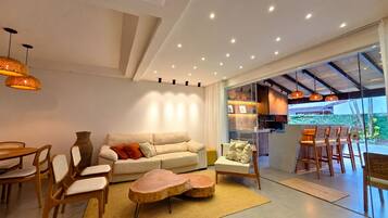 Uma sala de estar moderna com sofá, cadeiras, mesa de centro e área de jantar com mesa e cadeiras.